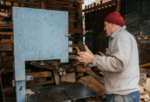 Home workshop owner using a wood bandsaw in a New Zealand shed workshop